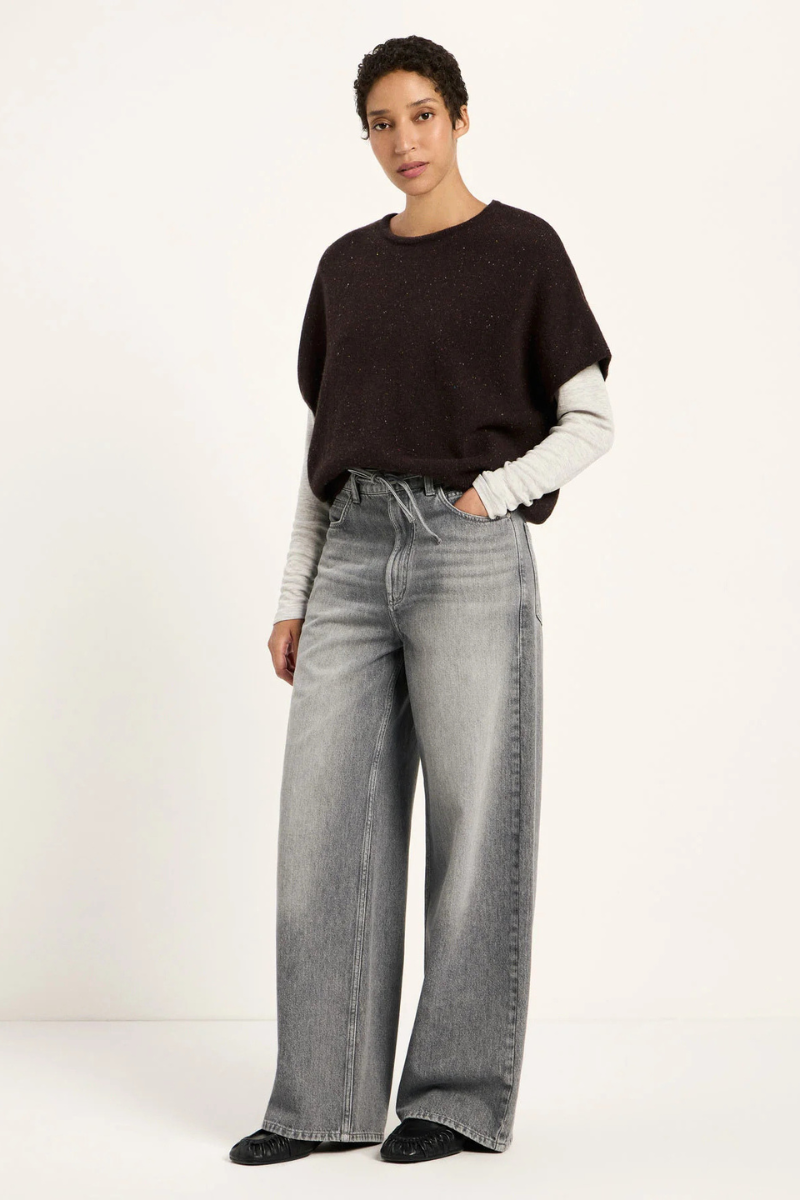 Frau trägt dunkelbraunen Pullunder kombiniert mit einem grauen Longsleeve und grauen Jeans und schwarzen Loafers