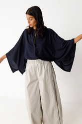 Frau trägt dunkelblaues Oversized-Hemd von SKFK mit weiten Kimonoärmeln