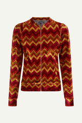 Retro-inspirierte Samtjacke von King Louie mit Chevron-Muster in Rot-, Orange- und Gelbtönen, Modell Iris Penny Cabern.