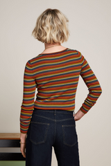 Modell trägt retro-inspiriertes Longsleeve mit Streifenmuster in orangenen Farbtönen mit einer dunkelblauen Jeans