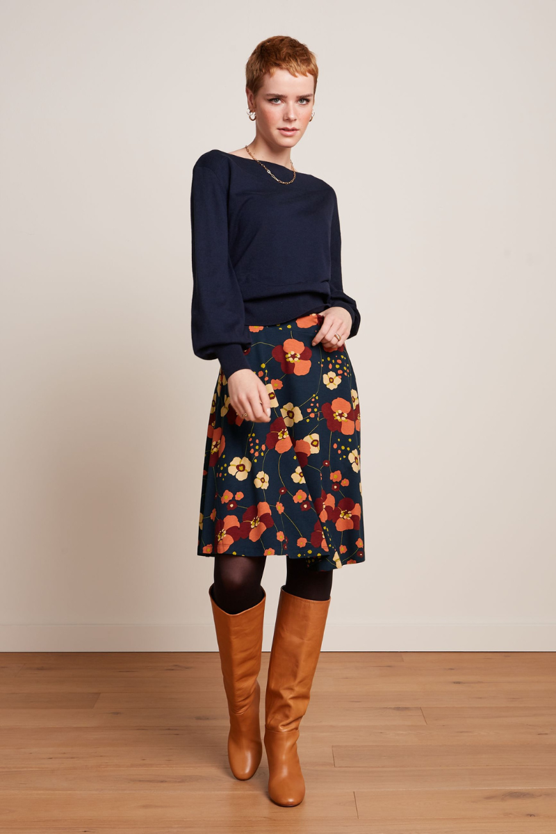 Ausgestellter dunkelblauer Rock mit grossem Blumenmuster von King Louie, kombiniert mit braunen Lederstiefeln und einem dunkelblauen Pullover mit Glockenärmeln